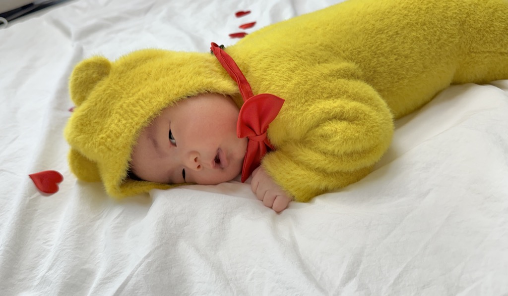 노란 곰 옷을 입고 포근하게 누워 있는 아기