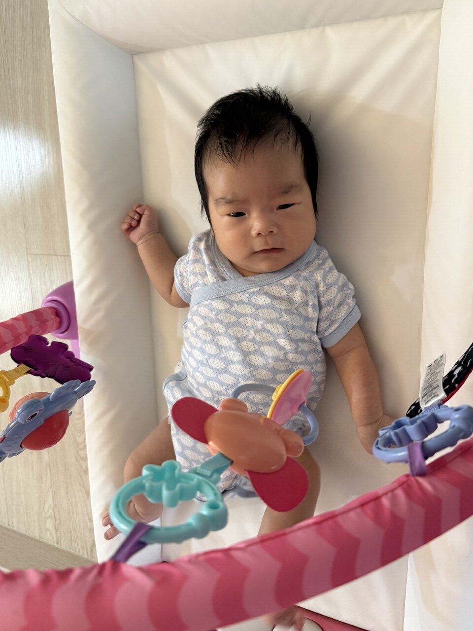 기저귀 갈이대에 누워 모빌을 보는 아이
